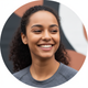 A close-up portrait of a smiling young woman in athletic wear, exuding satisfaction and trust.